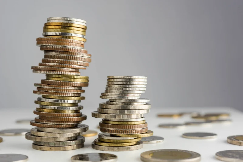 Stacked international coins representing consistent savings, positive cash flow management, and long-term wealth building for American expats in Thailand