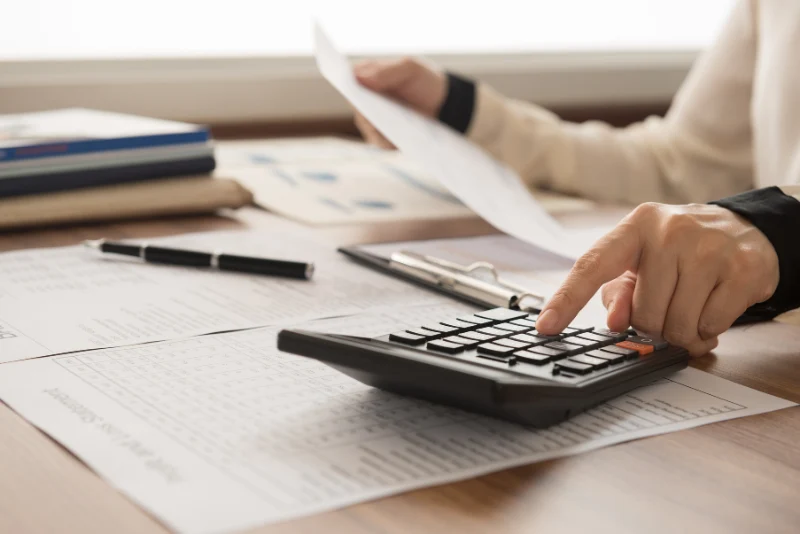 Financial advisor using a calculator to review insurance documents and coverage requirements for an American expat in Thailand