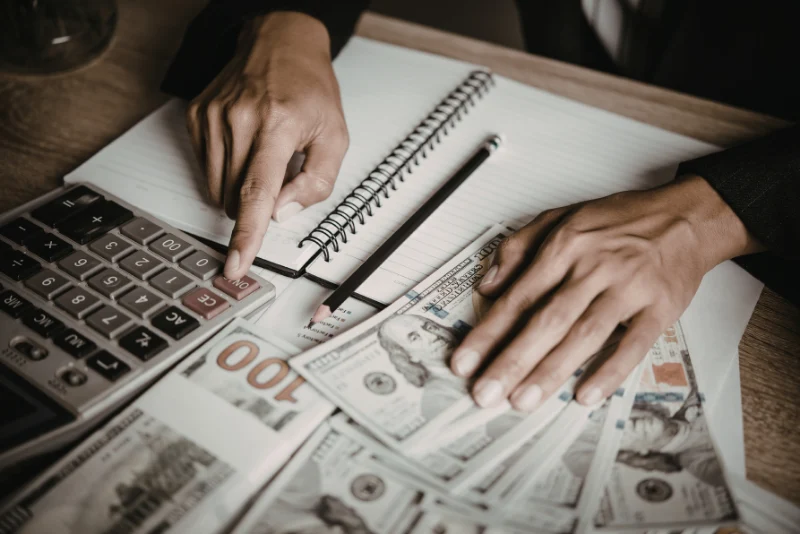 Calculator with US dollar bills and financial notepad representing insurance premium calculations and personal coverage planning for American expats living in Thailand