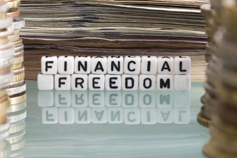 Financial freedom letter tiles surrounded by coins and banknotes representing the goal of asset protection planning for American expats building wealth in Thailand