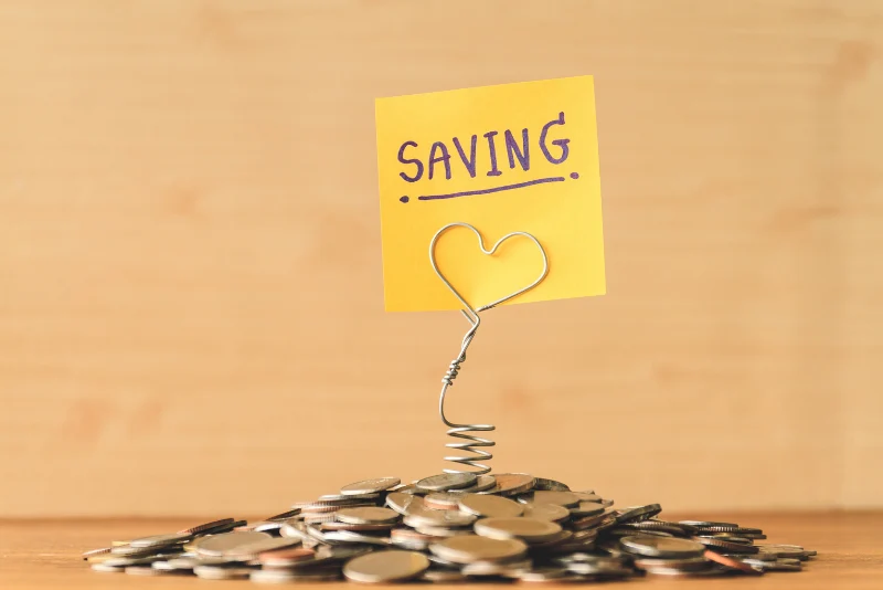 Saving money concept with sticky note and pile of coins representing personal budgeting fundamentals and savings strategies for American expats managing finances abroad