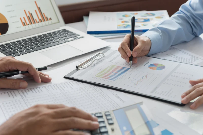 Business advisors reviewing corporate tax planning charts and financial reports for American expat business owners operating companies in Thailand