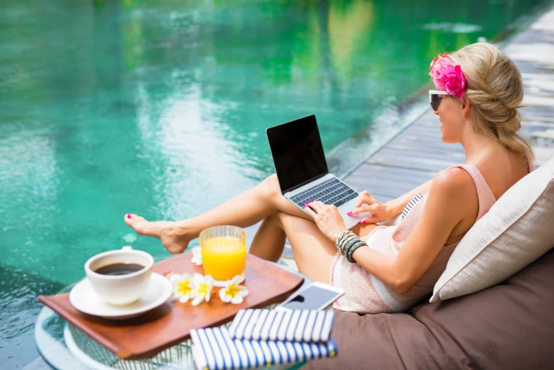 American expat woman working on laptop by a tropical pool in Thailand representing the digital nomad and expat lifestyle supported by community and networking resources