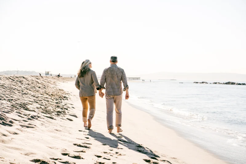 Retired American expat couple walking hand in hand on a beach in Southeast Asia enjoying a financially secure retirement in Thailand